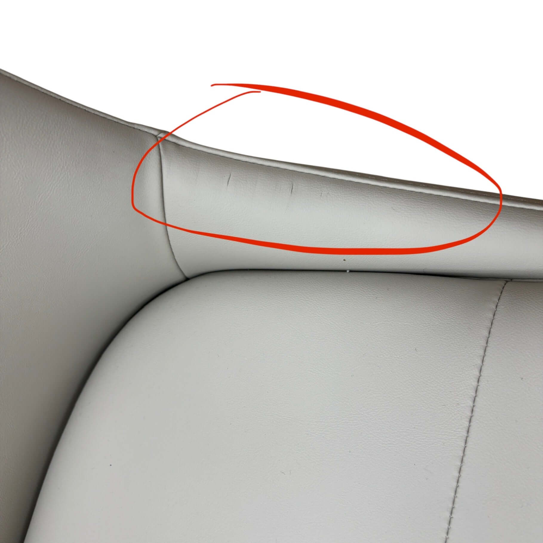 Car interior with a red circle highlighting a seam or defect on the gray leather.