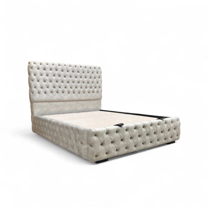 Side profile view of the Belford velvet bed, showing the full height of the floor-standing headboard and the streamlined base.