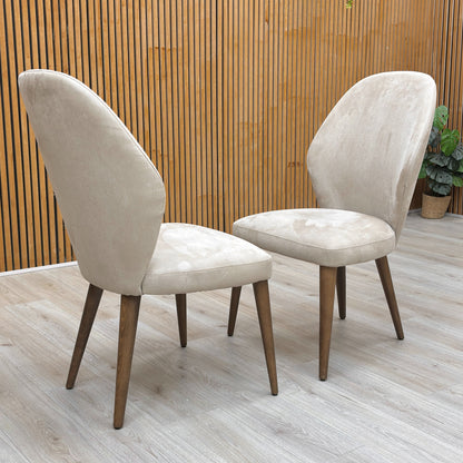 Lifestyle shot of the satin taupe Emperor chairs in a modern, highlighting the elegant curved backrest and padded seat.