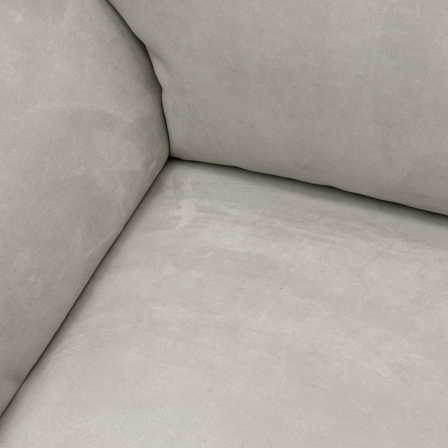 Close-up detail of the padded armrest and the luxurious texture of the Silver Suede fabric on the sofa.