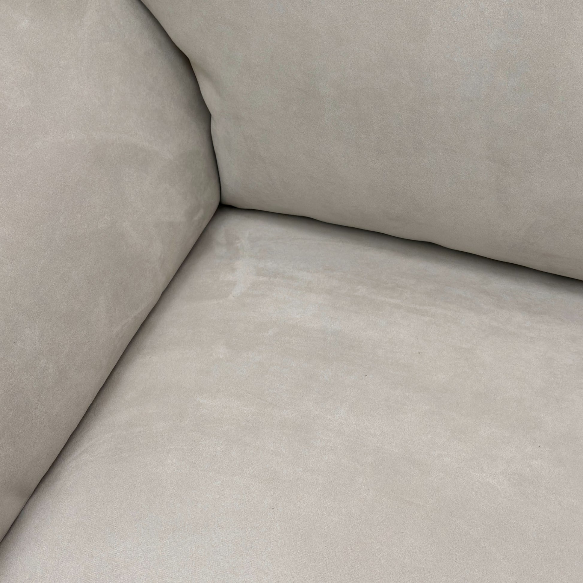 Close-up detail of the padded armrest and the luxurious texture of the Silver Suede fabric on the sofa.