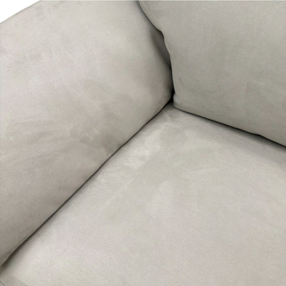 Close-up showing the soft silver suede fabric texture and the detailed piping along the sofa's edges.