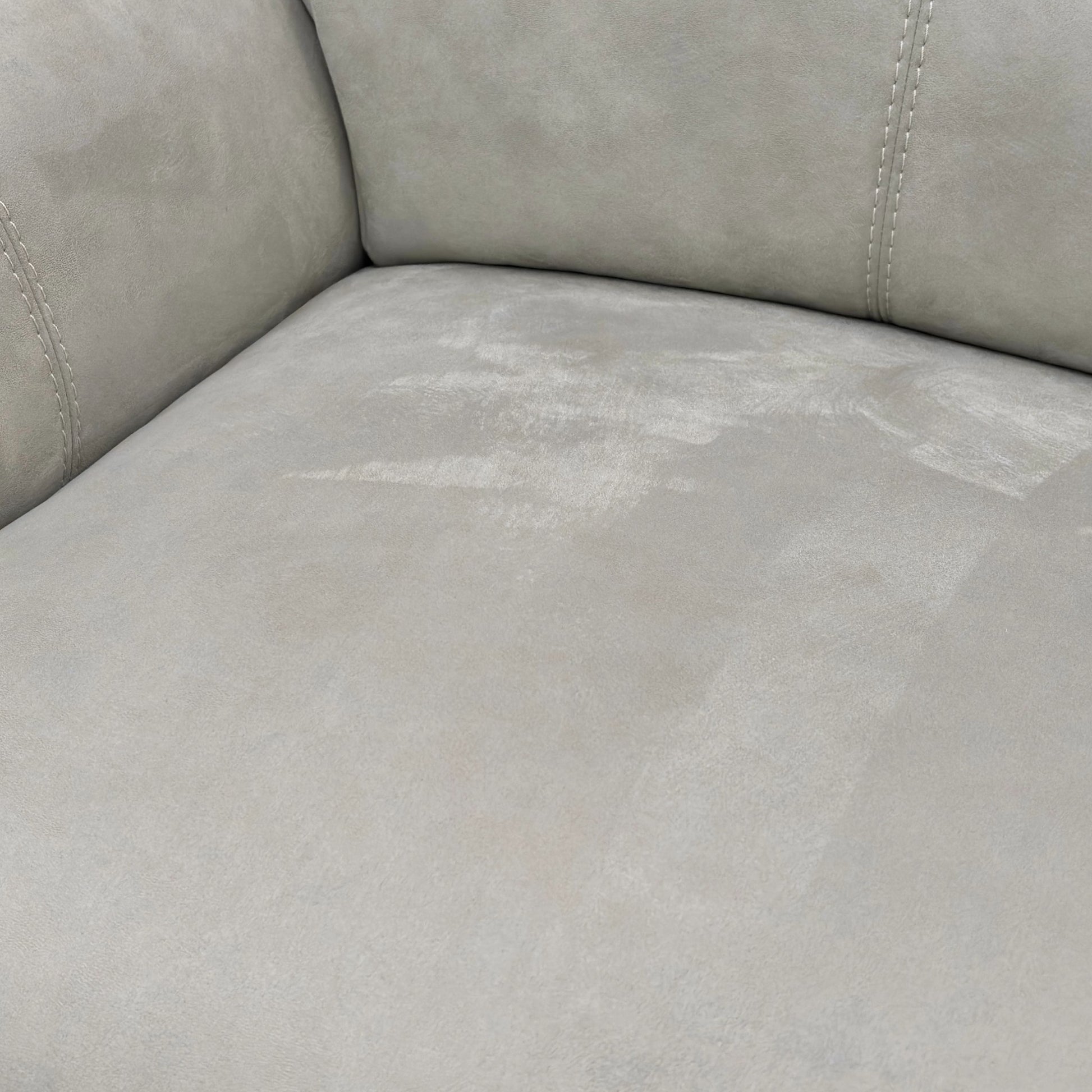 Extreme close-up detail of the bluish-grey suede fabric upholstery, showing the soft texture and subtle colour variation.