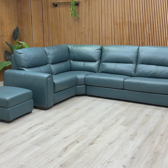A video of Green leather sectional sofa with ottoman on a wooden floor against a wooden wall.