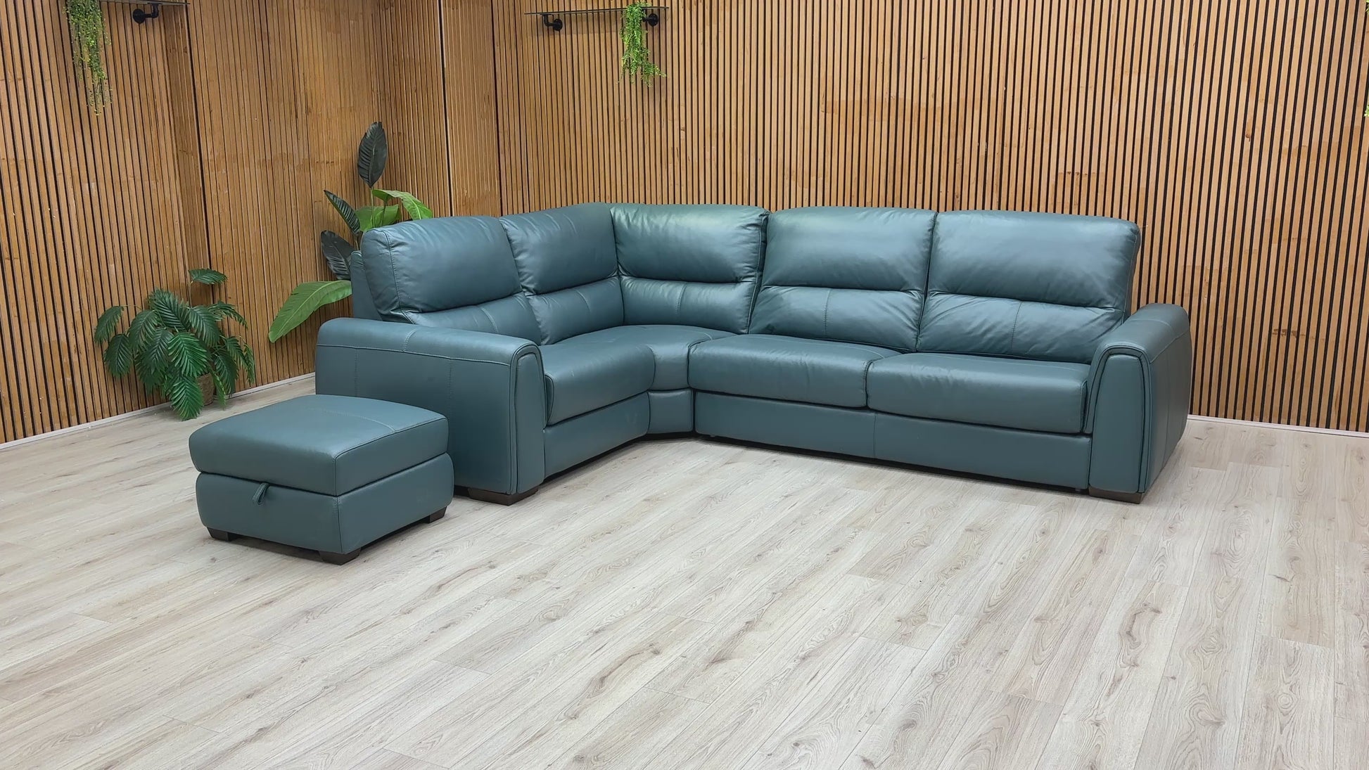 A video of Green leather sectional sofa with ottoman on a wooden floor against a wooden wall.
