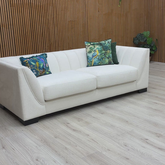 A video of White sofa with decorative pillows against a wooden wall.