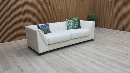 A video of White sofa with decorative pillows against a wooden wall.