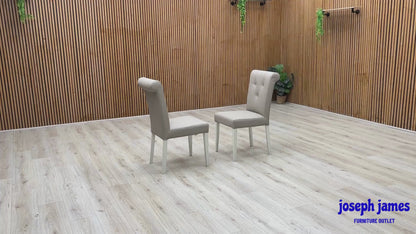 Video Of ‘Furnitureland Annecy’ dining chair set, showcasing a matching pair of two roll-back dining chairs with a soft grey painted finish and faux leather upholstery.