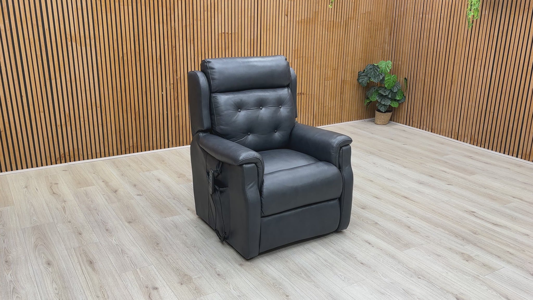 A video of a Black leather power recliner with footrest extended with a Wooden Background