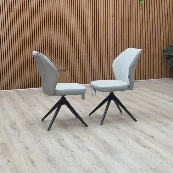 Video Of ‘Julio’ contemporary dining chairs, featuring a matching set of 2 elegantly sculpted seats upholstered in high-grade Stone Grey fabric with a sleek black metal base frame.