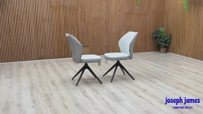 Video Of ‘Julio’ contemporary dining chairs, featuring a matching set of 2 elegantly sculpted seats upholstered in high-grade Stone Grey fabric with a sleek black metal base frame.