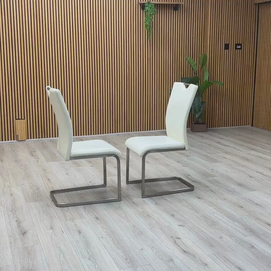 Video Of ‘Bianco’ contemporary dining chair set, showcasing a pair of sleek chairs beautifully upholstered in crisp White faux leather supported by minimalist chrome cantilever bases.