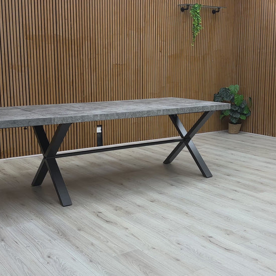 A video of Long rectangular table with a concrete top and black metal legs against a wooden wall.