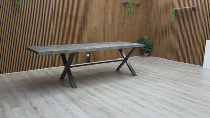A video of Long rectangular table with a concrete top and black metal legs against a wooden wall.