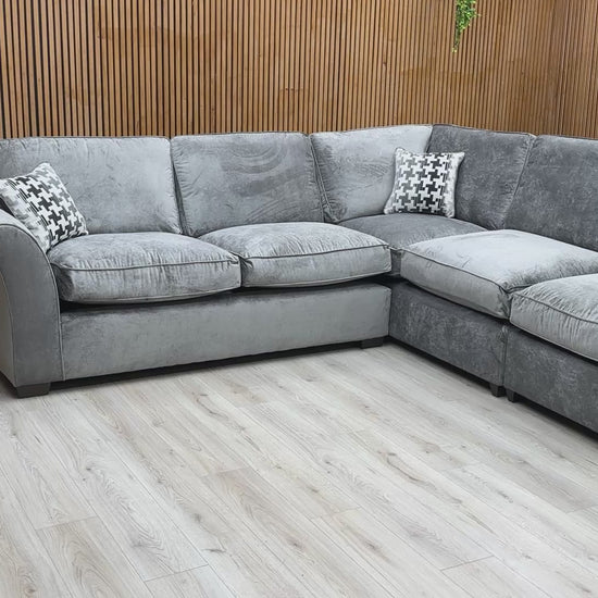 Product tour video of the Rosie Kingston Grey fabric corner sofa, demonstrating the cushion softness and the scale of the chaise arrangement.