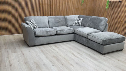 Product tour video of the Rosie Kingston Grey fabric corner sofa, demonstrating the cushion softness and the scale of the chaise arrangement.