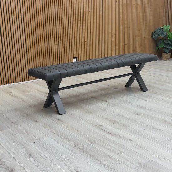 A video of Gray bench with X-shaped legs on a wooden floor against a wooden wall.