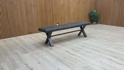 A video of Gray bench with X-shaped legs on a wooden floor against a wooden wall.