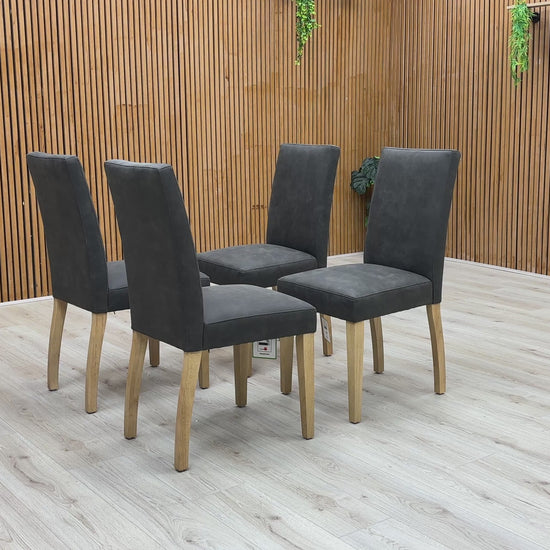 A video of Four dark gray chairs with wooden legs on a wooden floor.