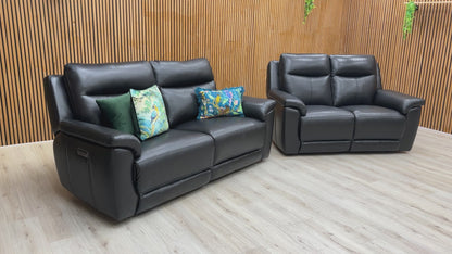 A video of Black leather sofa and recliner chair in a room with wooden walls and ceiling lights.