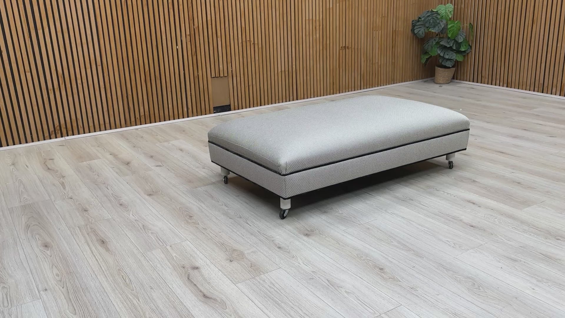 Video showcasing the scale and fabric texture of the Ambassador Allure Noir footstool in a room setting.