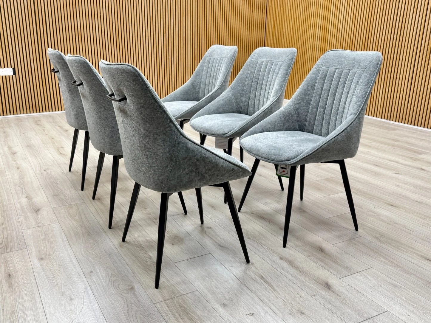 Lifestyle view of a Crete dark grey upholstered swivel dining chair featuring a modern curved silhouette and foam-padded seat.
