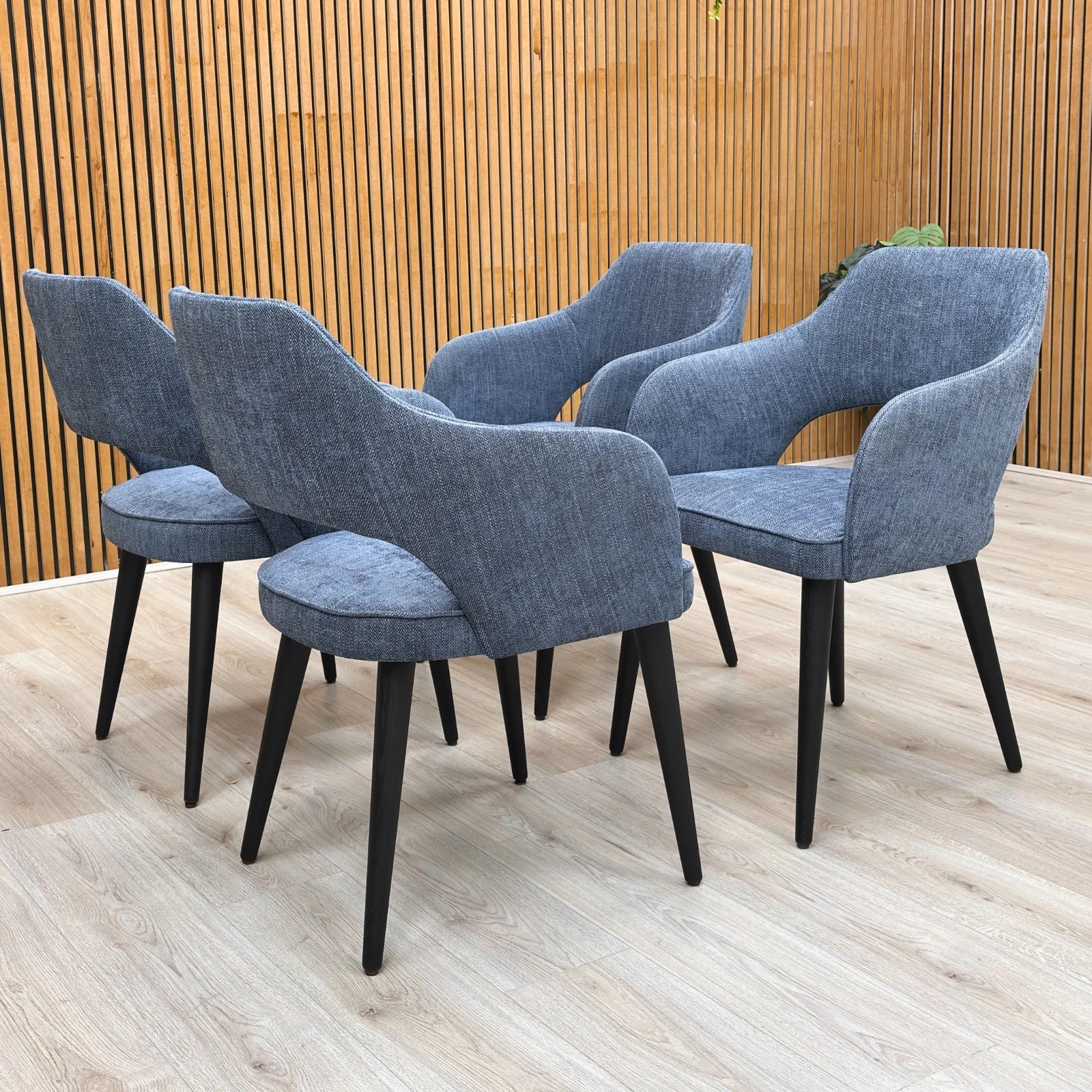 Stylized lifestyle shot of the navy blue Manu dining chairs, highlighting the contemporary curved backrest.