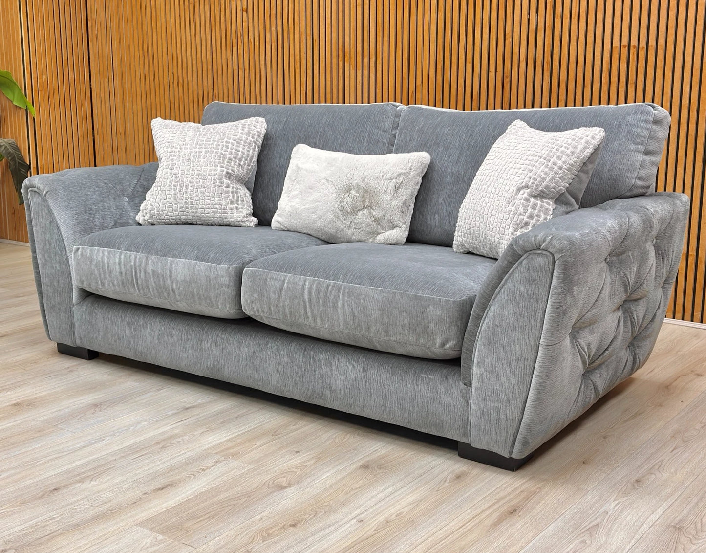 Lifestyle shot showing the elegant curved arms and button detailing of the 'Aphrodite' sofa.