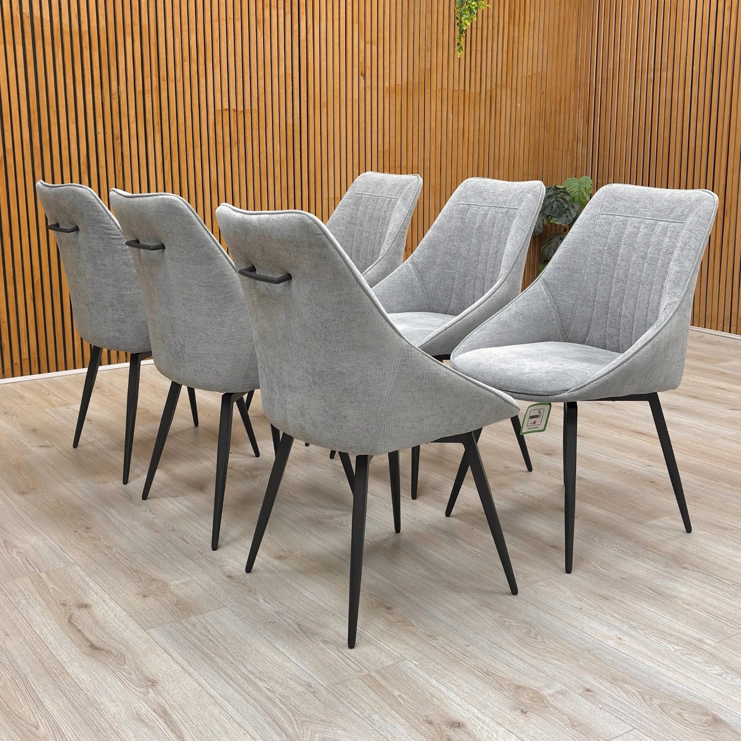 Lifestyle view of a silver velvet swivel dining chair featuring a modern curved silhouette and slender matt black metal legs.