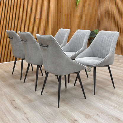 Lifestyle view of a silver velvet swivel dining chair featuring a modern curved silhouette and slender matt black metal legs.