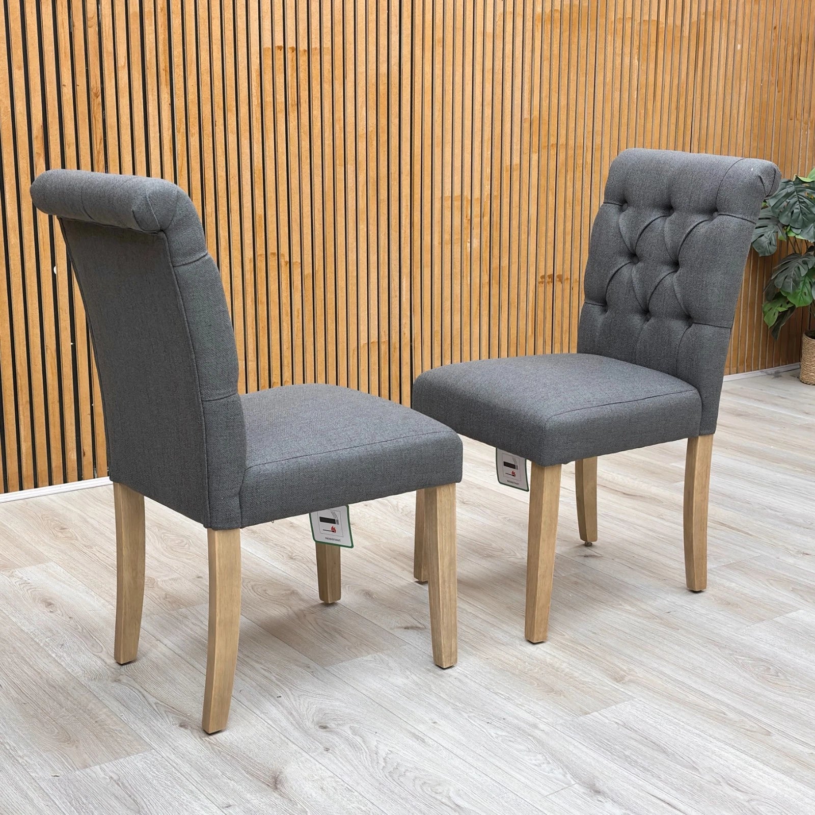 Stylized lifestyle shot of the ‘Lewis’ anthracite dining chairs, highlighting the elegant roll-back top and high-back design.