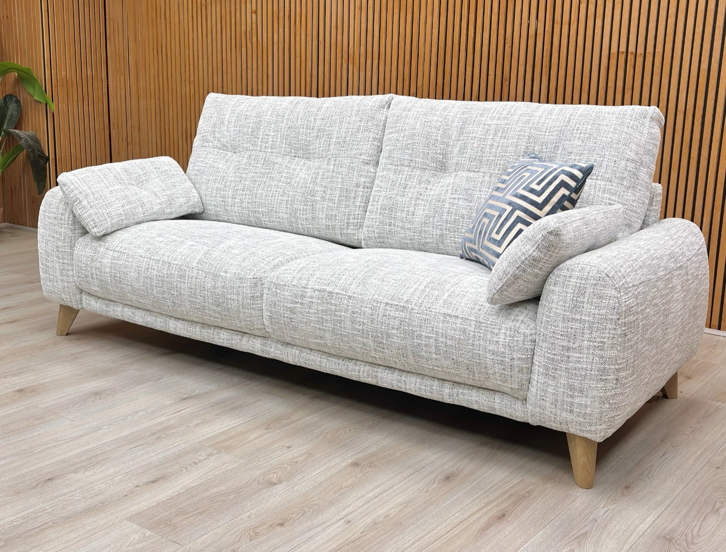 Lifestyle shot of the Malmo Silver Green 3-seater sofa in a contemporary living room, featuring subtle buttoning detail and two matching bolster cushions.