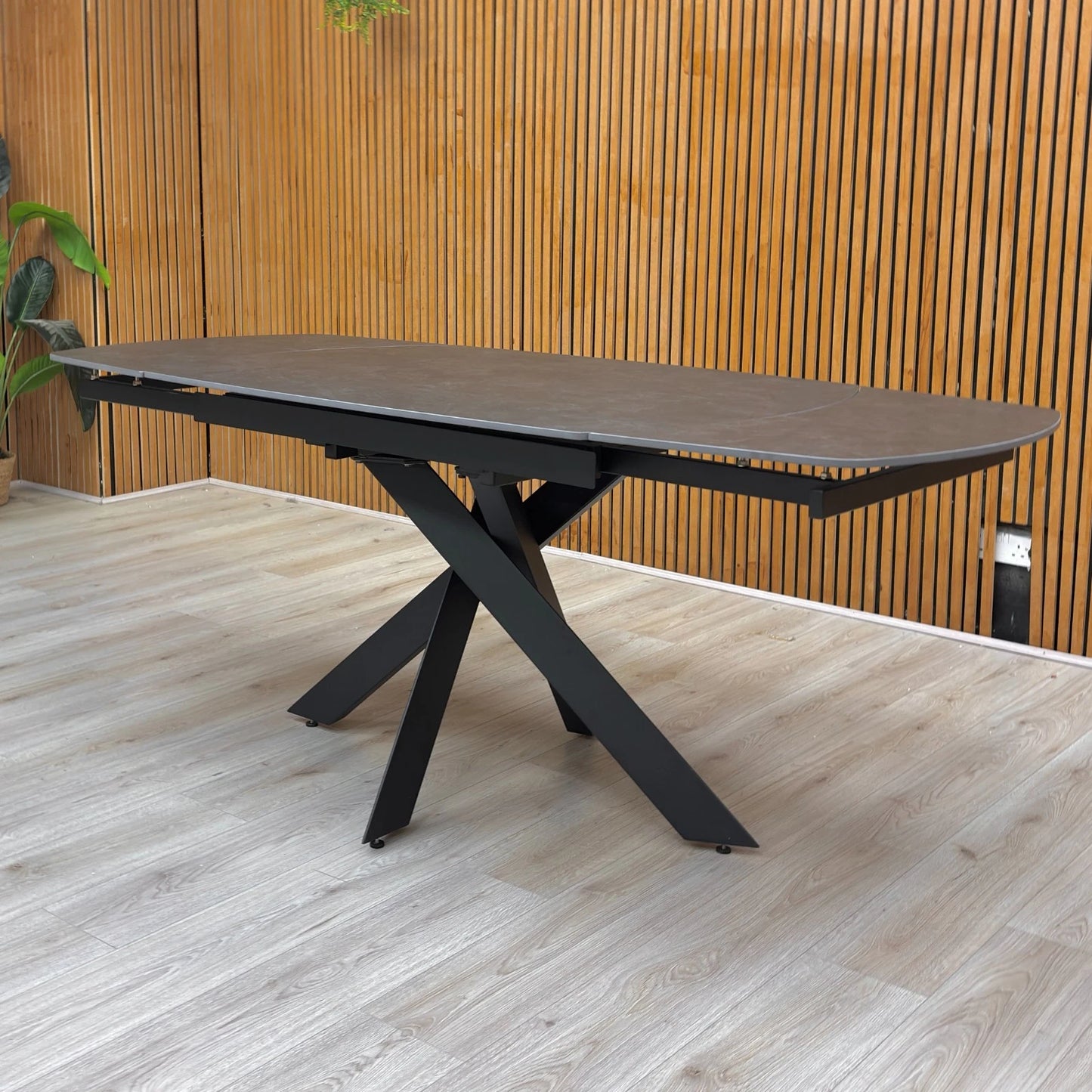 Lifestyle shot of the ‘Warrior’ dining table, highlighting the industrial matt finish and asymmetric base.