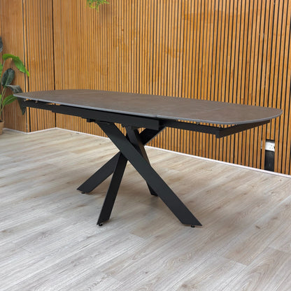 Lifestyle shot of the ‘Warrior’ dining table, highlighting the industrial matt finish and asymmetric base.