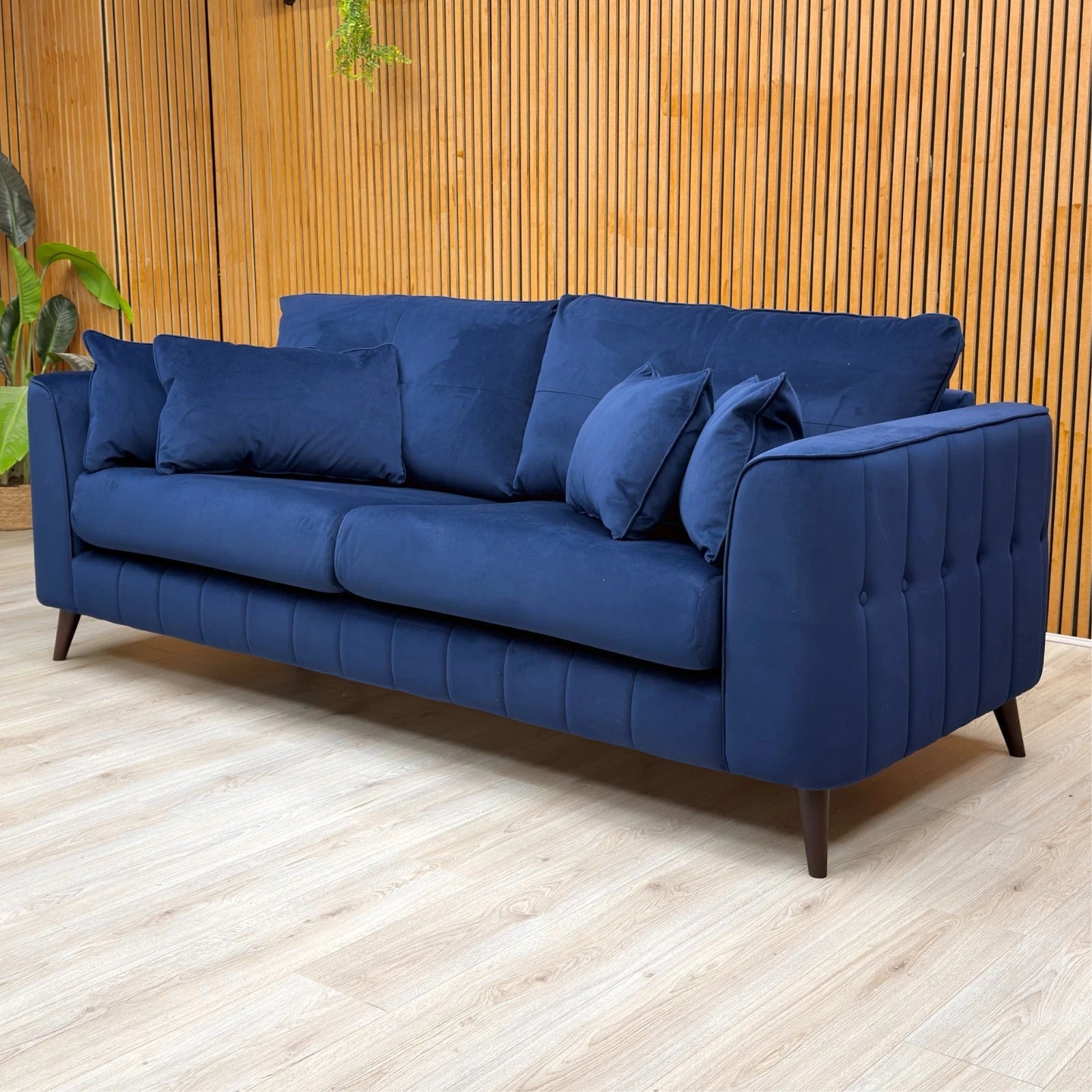 Lifestyle shot of the Royal Blue ‘Remy’ 4-seater sofa, showcasing its large seating capacity and elegant, bold presence in a living room.