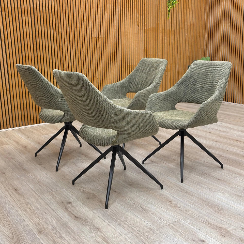 A set of four ‘Charlotte’ Sage Green Tweed Swivel Dining Chairs arranged around a modern dining table.