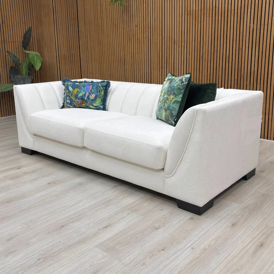 White sofa with decorative pillows against a wooden wall.