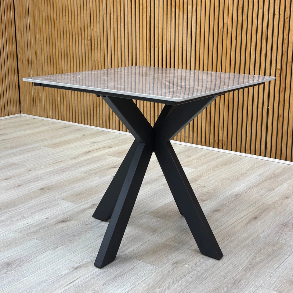 Lifestyle shot of the square table, showcasing the modern silhouette and industrial metal legs.