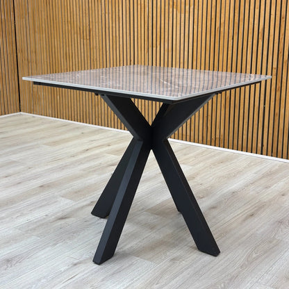 Lifestyle shot of the square table, showcasing the modern silhouette and industrial metal legs.
