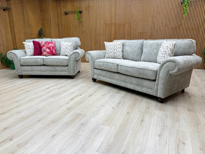 Side view of the 'Clara' sofa, illustrating the depth, wooden block feet, and the classic scroll arm design.