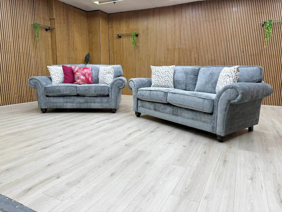 Side profile of the 'Clara' sofa, illustrating the deep seating, wooden block feet, and classic scroll arm design.