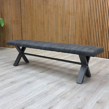 Gray bench with X-shaped legs on a wooden floor against a wooden wall.
