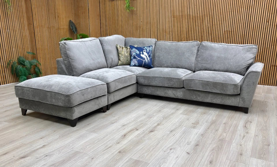 Lifestyle shot of the ‘Legend’ Kingston Grey fabric corner sofa in a modern lounge, highlighting its spacious seating and contemporary style.