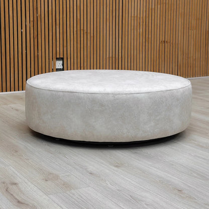 The Mariah twister footstool placed in a room setting, showing the creamy color and velvet-like texture of the nubuck leather-look base