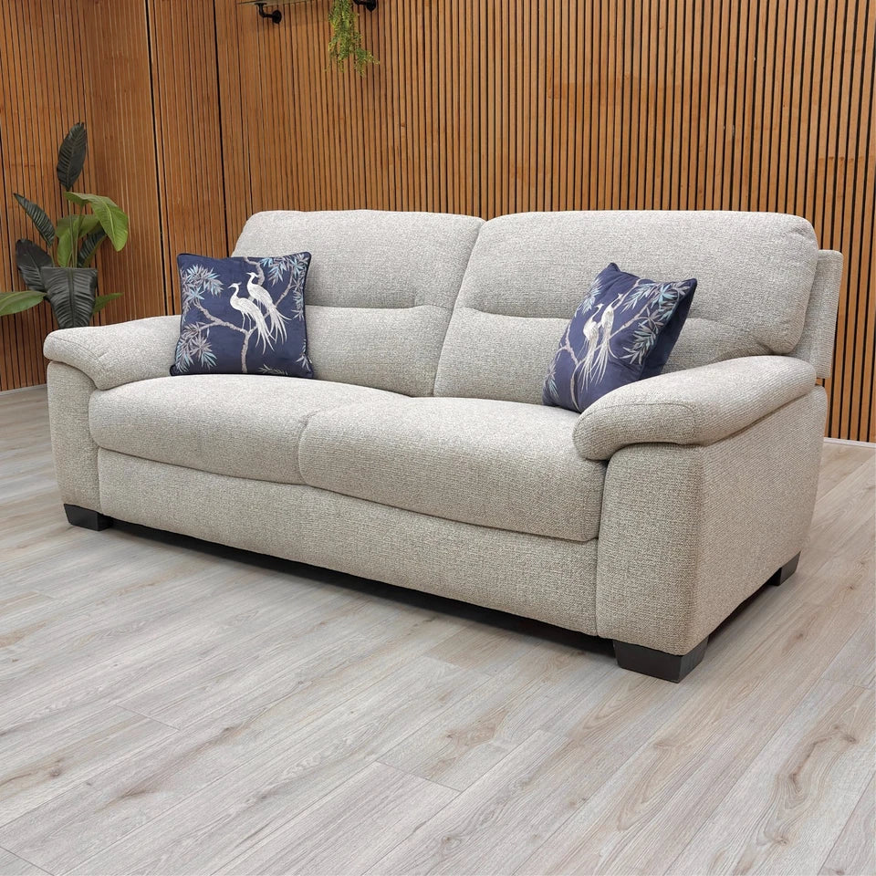 Beige sofa with decorative pillows on a wooden floor and wall background