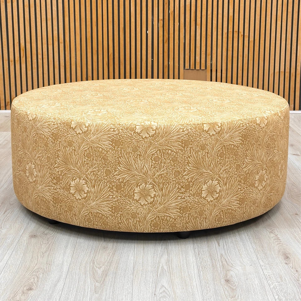 Front view of the Iris footstool, highlighting the rich yellow velvet fabric and the intricate floral pattern details.