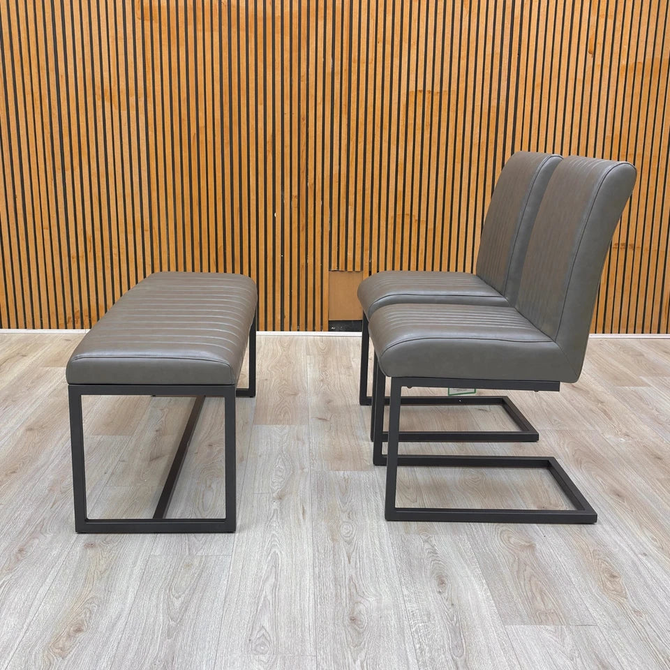 Lifestyle view of the 'Arthur' dining set featuring the 120cm grey faux leather bench and two cantilever chairs.