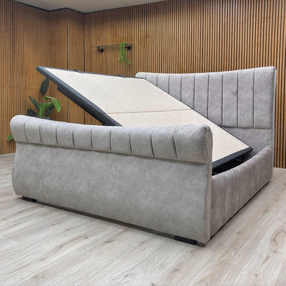 Gray upholstered bed with tufted design in a room with wooden walls and floor.