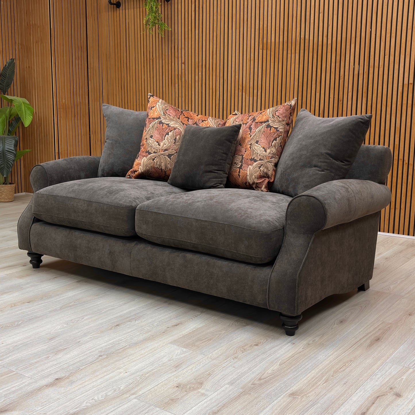 Gray sofa with patterned cushions in a room with wooden walls and floor.