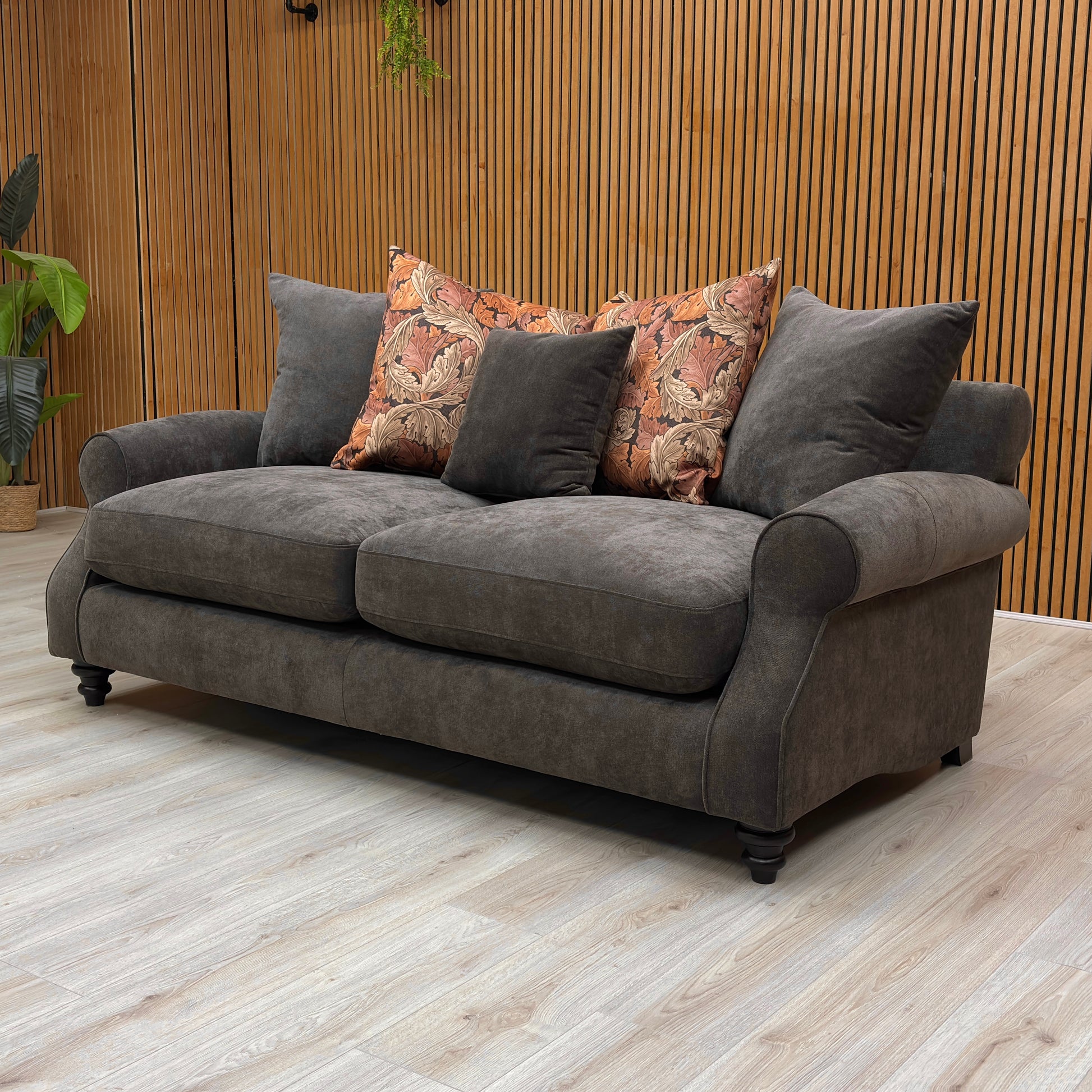 Gray sofa with patterned cushions in a room with wooden walls and floor.